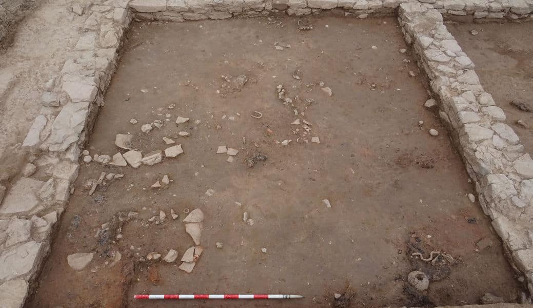 The room contains the remains of burnt beams, iron elements possibly associated with a door, and various pottery pieces